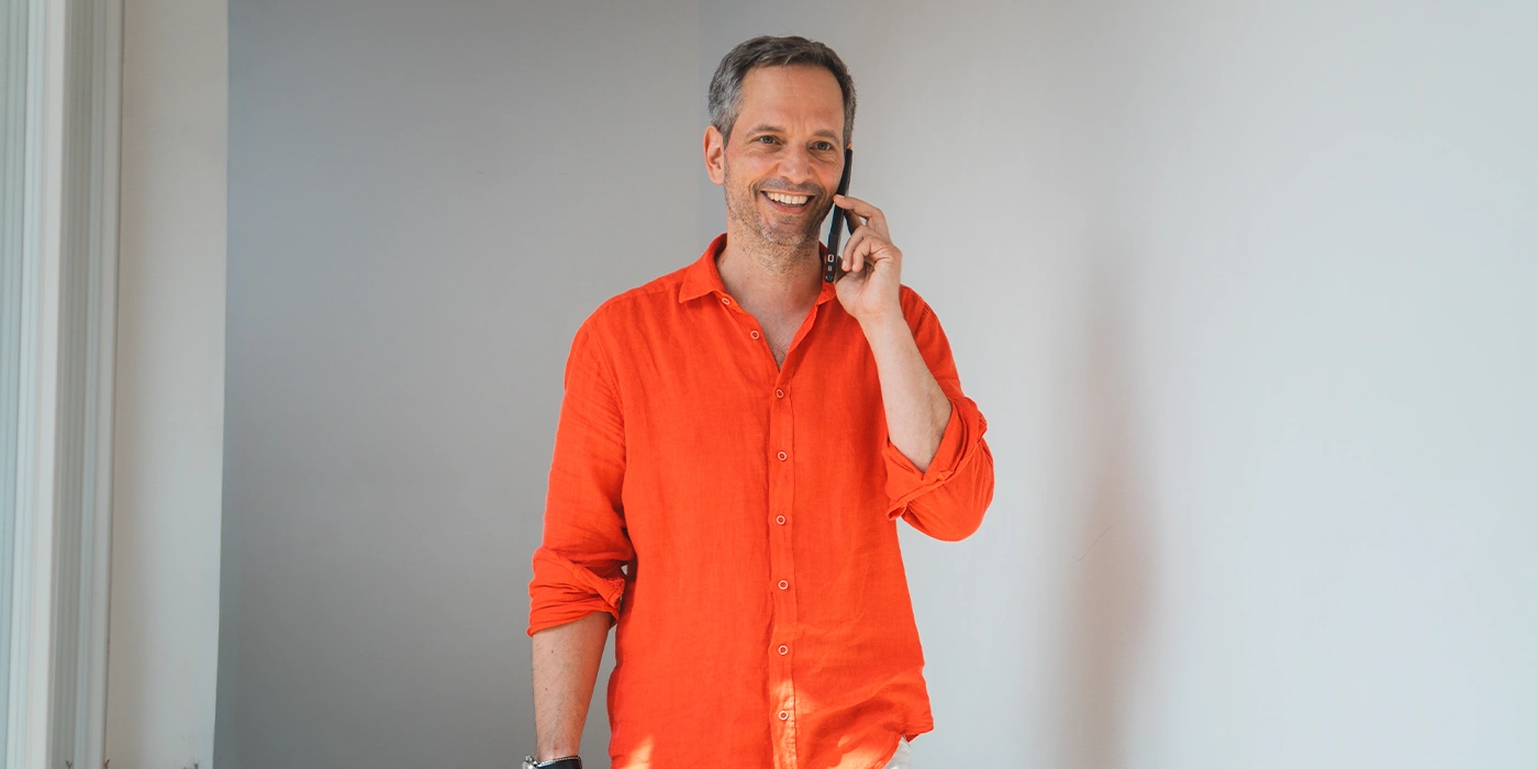 ueber-uns-thomas-hubinger-versicherungsmakler-hubinger Versicherungsmakler Hubinger telefoniert am Handy, lächelt dabei