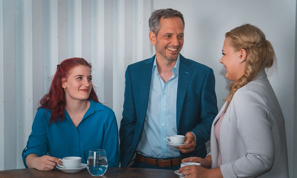 ueber-thomas-hubinger-team-versicherungsmakler-hubinger Versicherungsmakler Hubinger im blauen T-Shirt steht lächelnd auf einer Brücke mit seinem Hund.